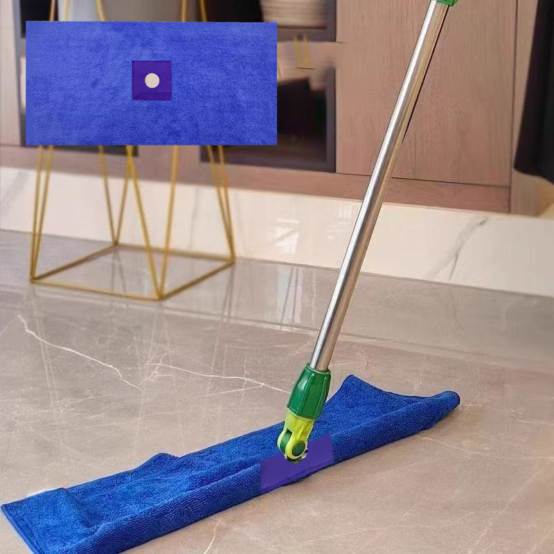 A mop head absorbing a large water spill on a tile floor