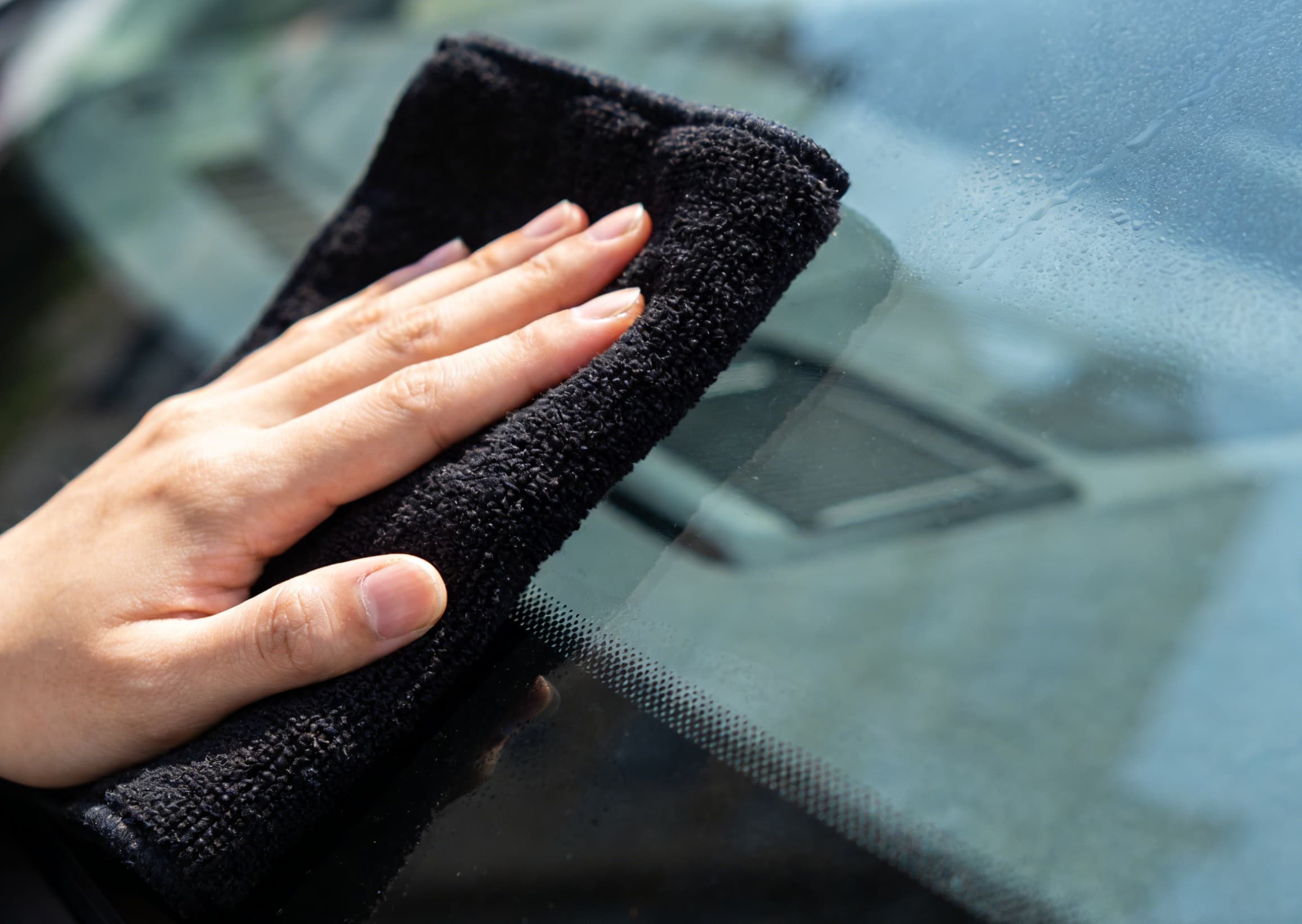 A black microfiber cloth on a car's surface