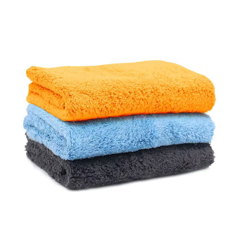 A stack of three microfiber towels in orange, blue, and dark gray on a white background