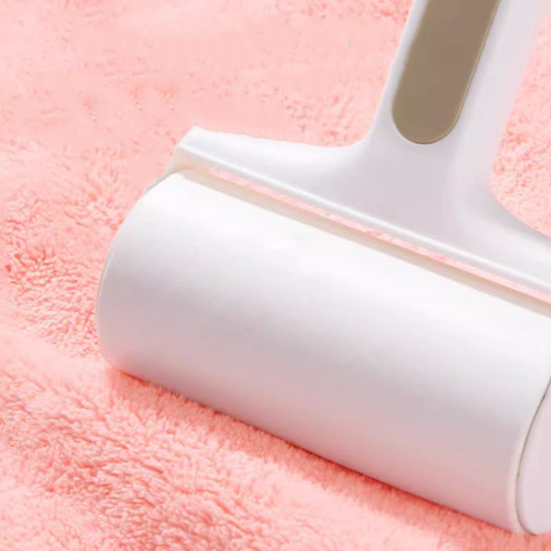 White lint roller gliding over pink coral fleece fabric to remove hair and dust