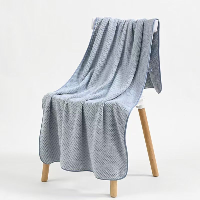 Gray-blue microfiber towel casually draped over a wooden chair in a minimal room
