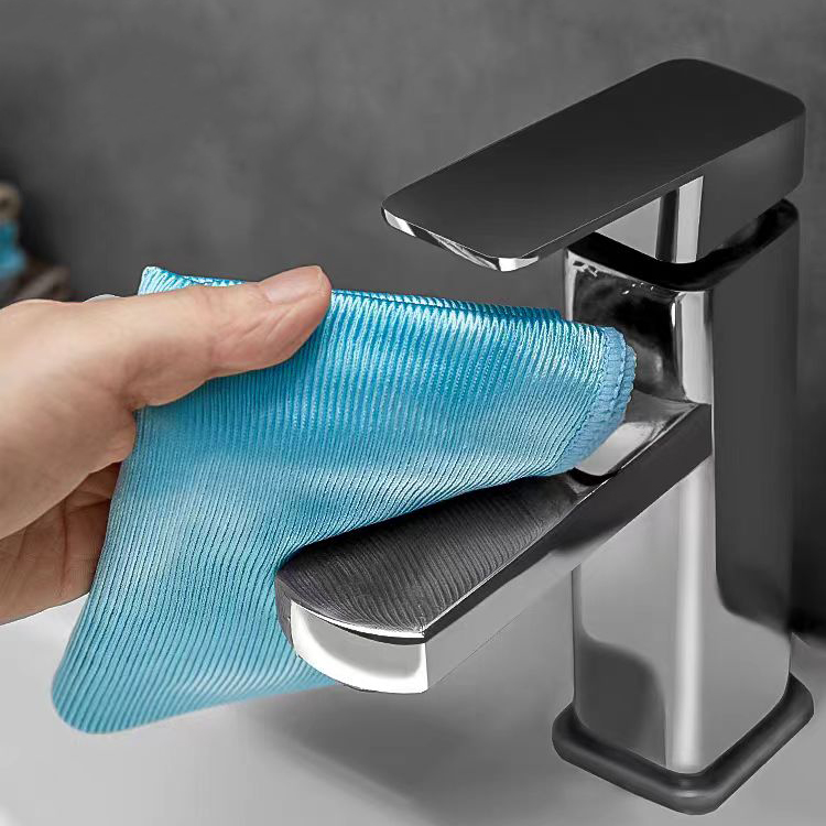 Person using blue glossy microfiber cloth to clean chrome faucet surface