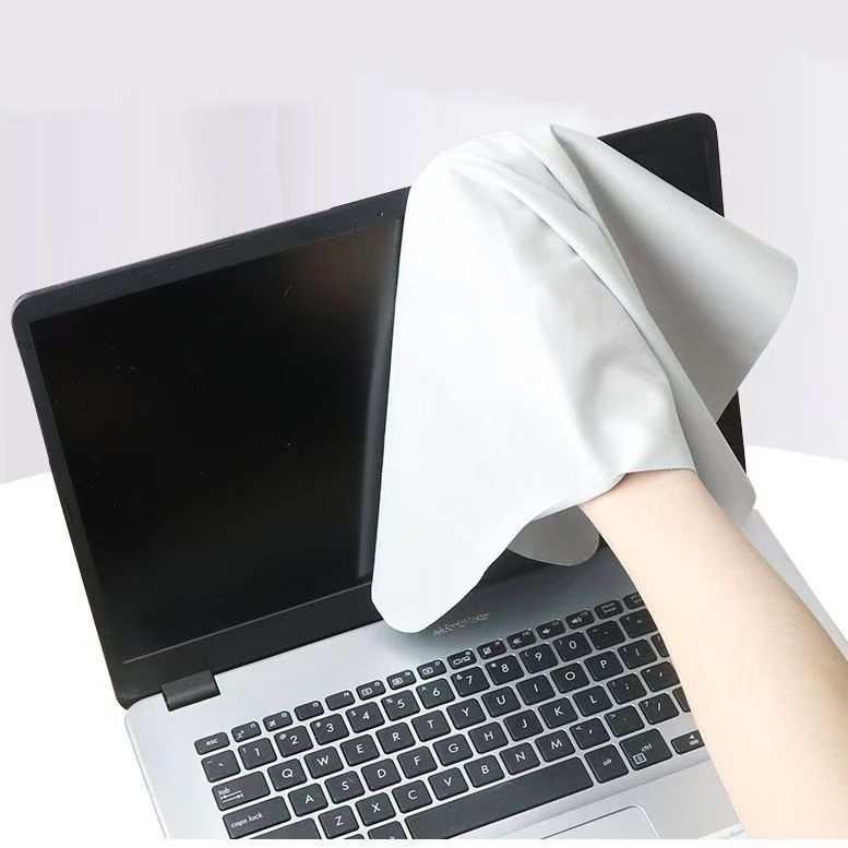 Person cleaning laptop screen using smooth white microfiber cloth