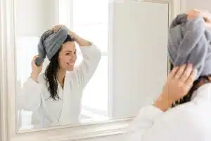 a woman wrapping her hair in a microfiber towel